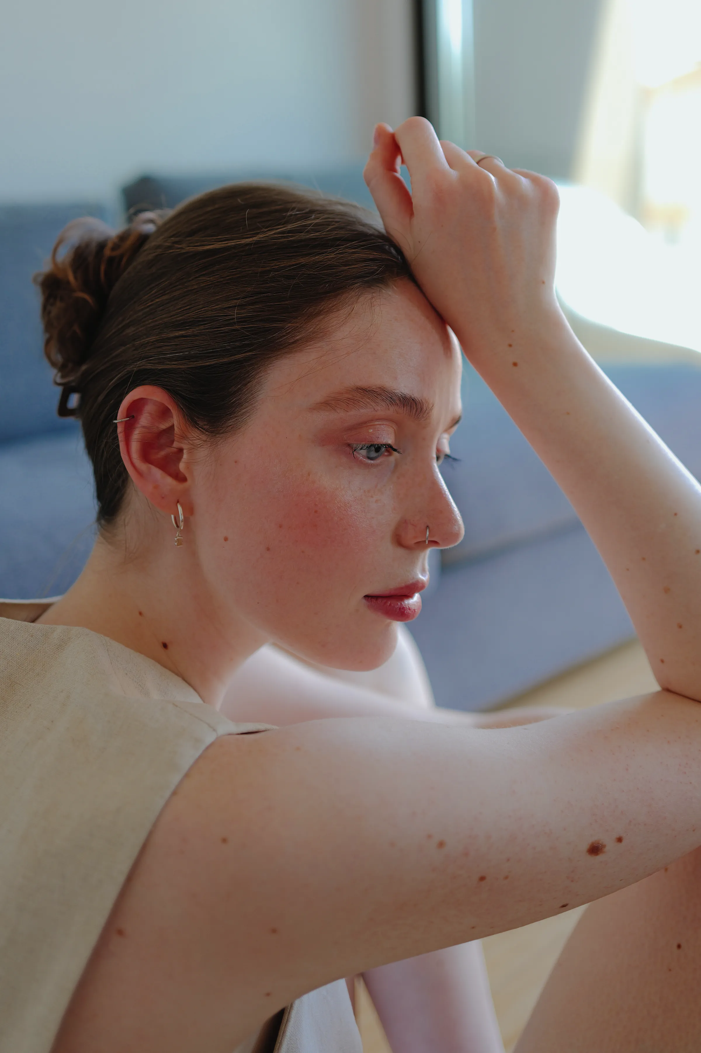 Close portrait of a woman resting her arm near a window in soft indoor light