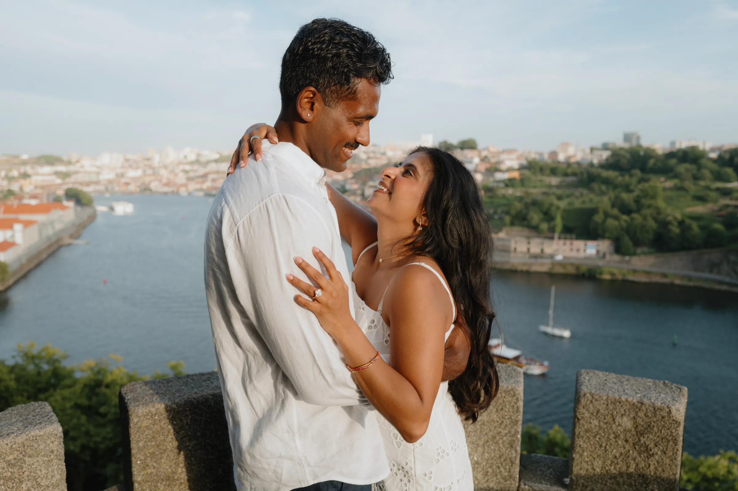 Couple portrait overlooking a river and city during an outdoor session in soft light.