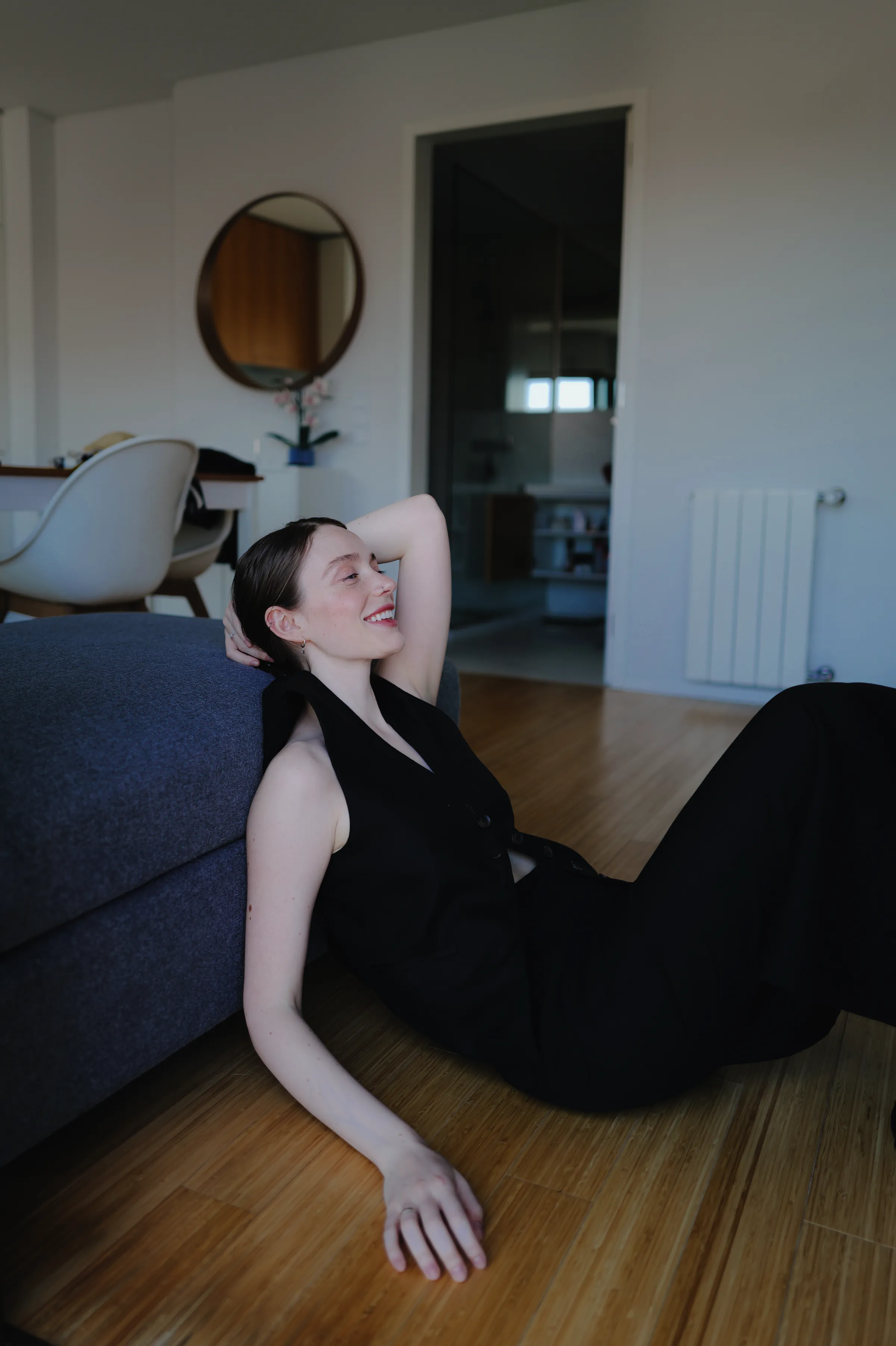 Home session portrait of a person seated on the floor beside a sofa in soft indoor light.