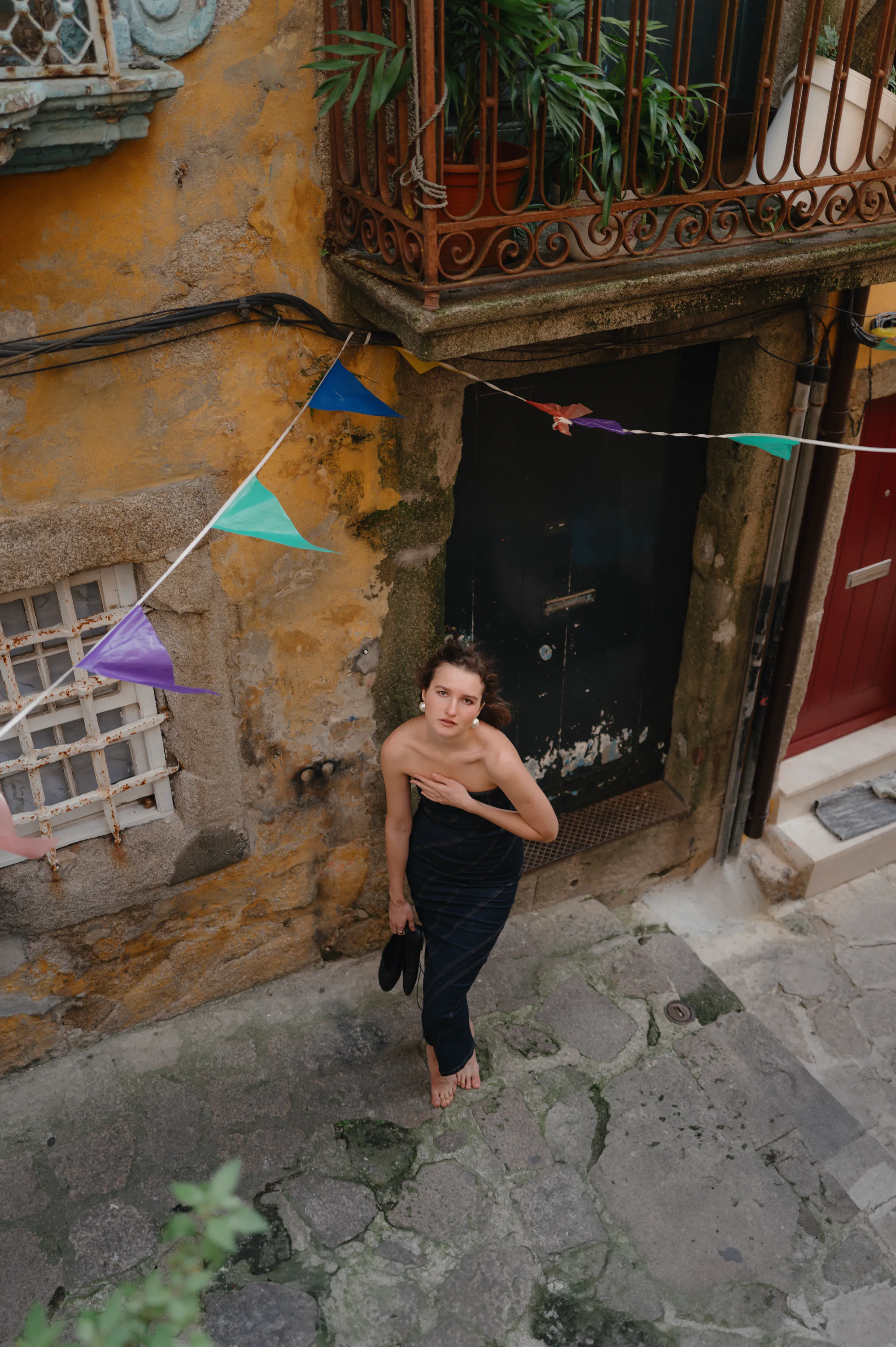 Portrait of a woman in a black dress on a narrow old city street beneath colorful bunting
