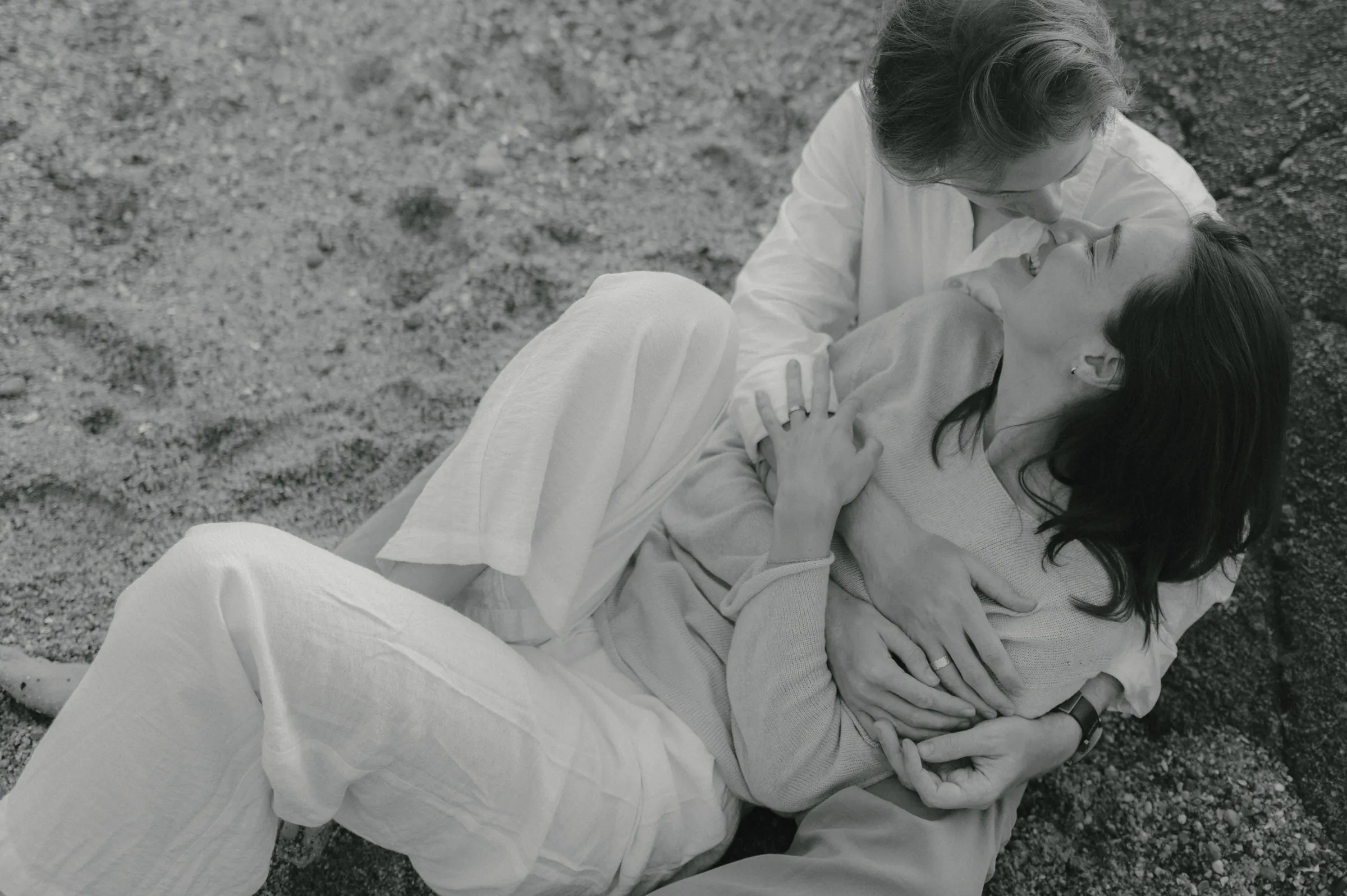 Adult and child in a close outdoor portrait on grass, captured in soft black-and-white tones.