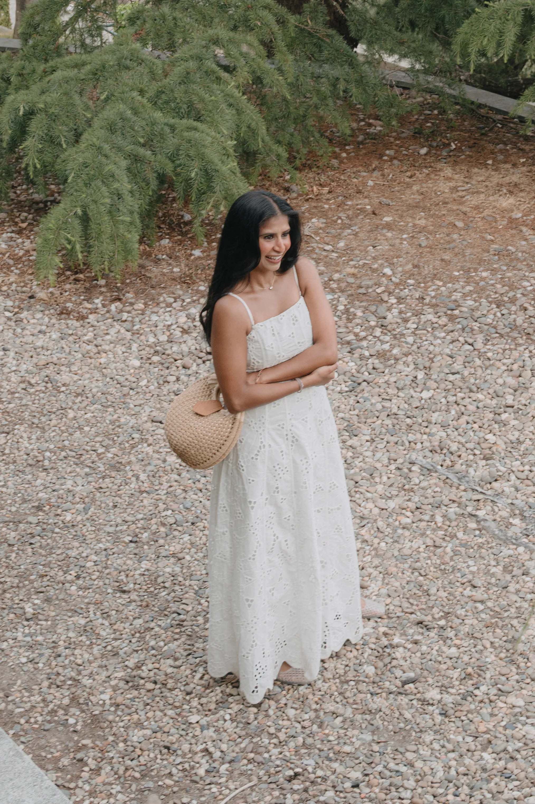 Outdoor portrait of a woman in a white dress on a gravel garden path in soft light