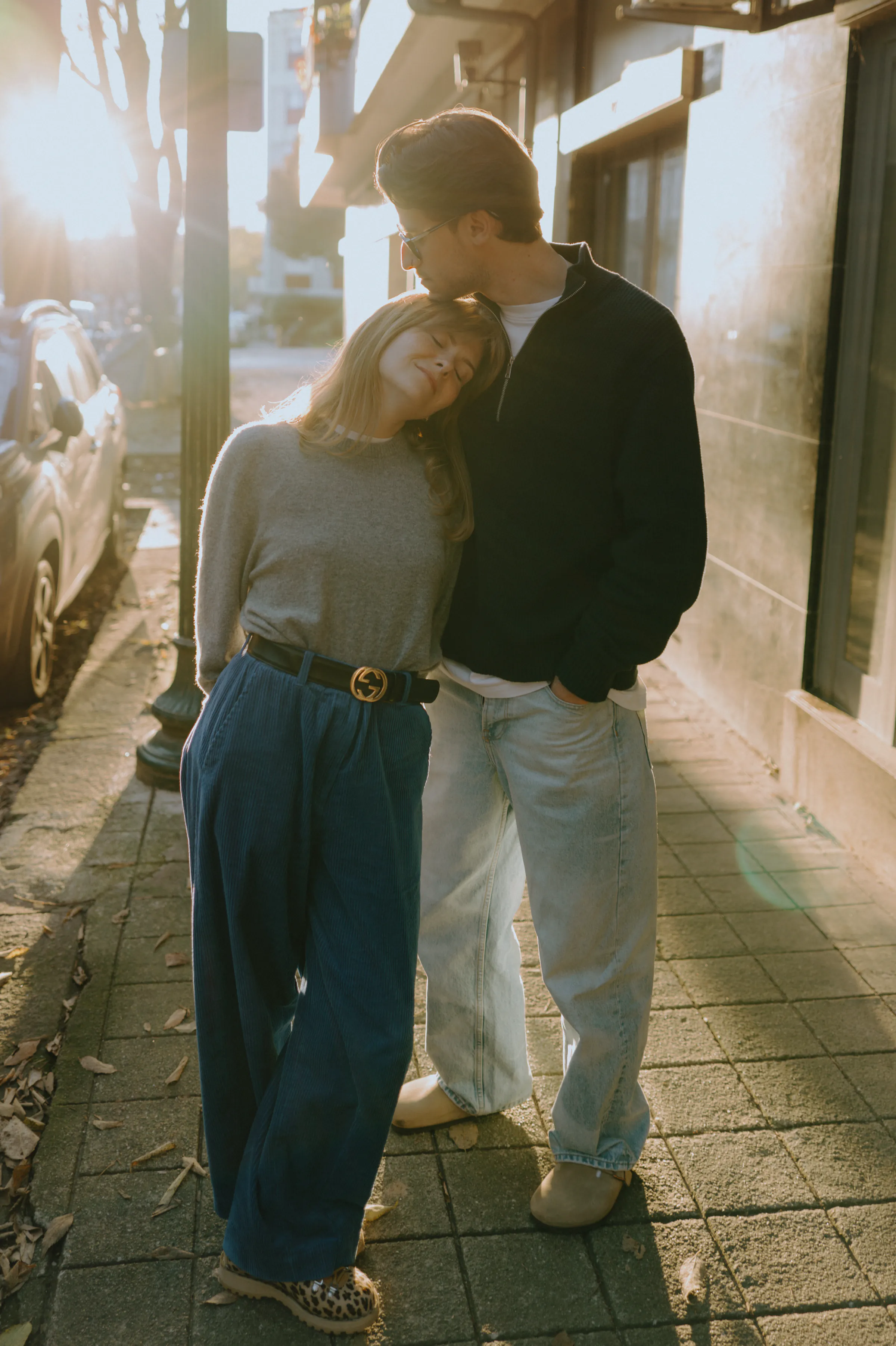 Couple leaning together during a soft light city walk on a sidewalk.