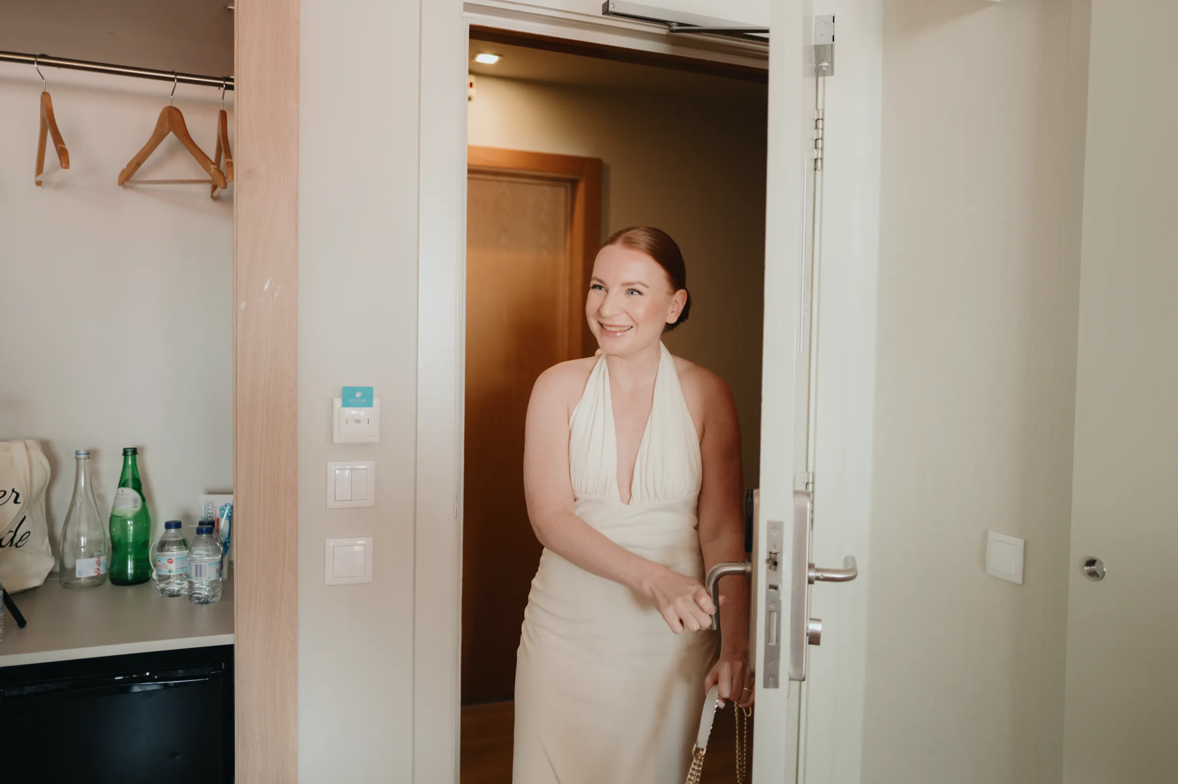 Portrait of a woman in a white dress standing in a doorway during an indoor session.