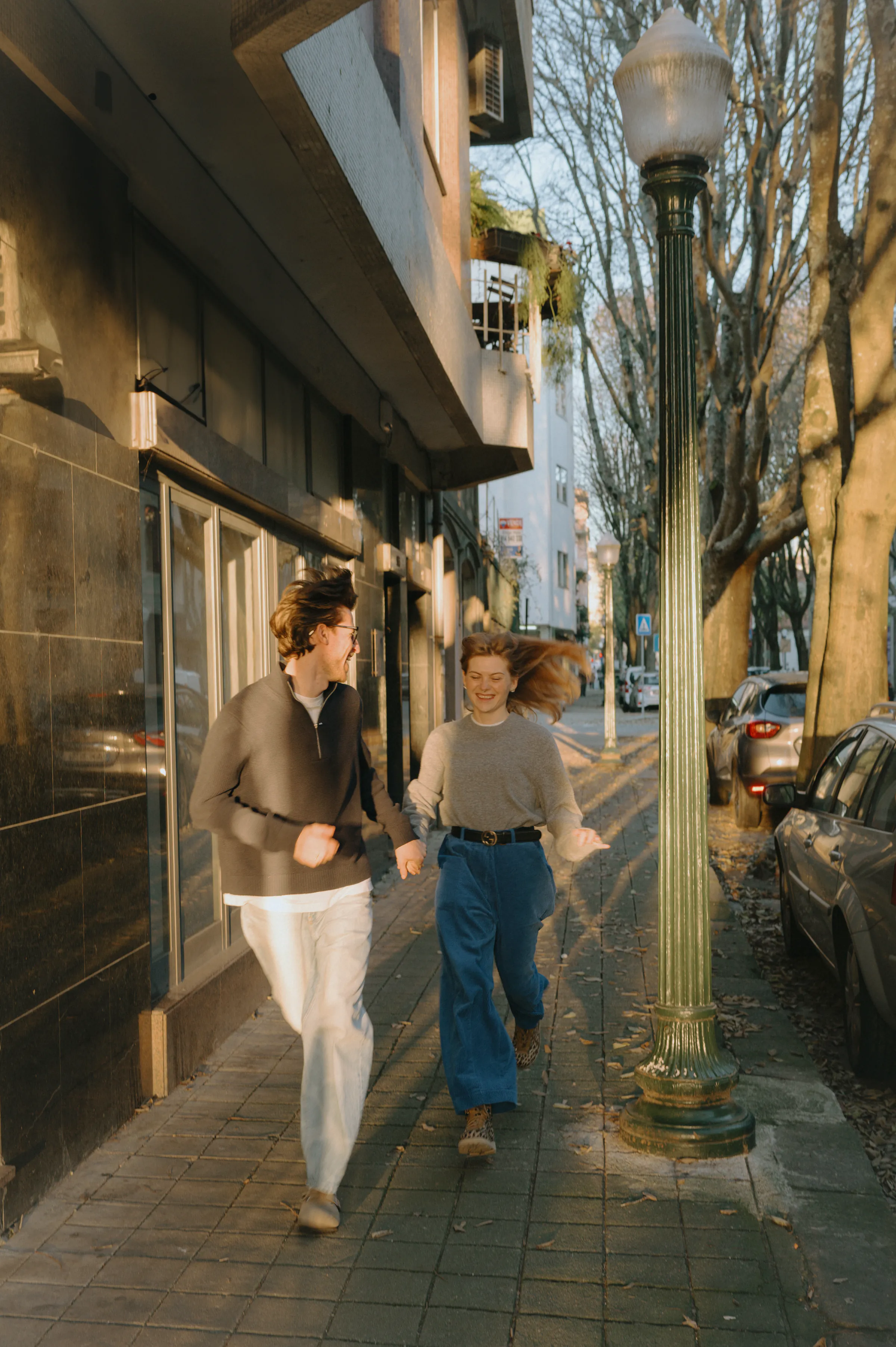 Couple walking hand in hand during a city walk in soft light.