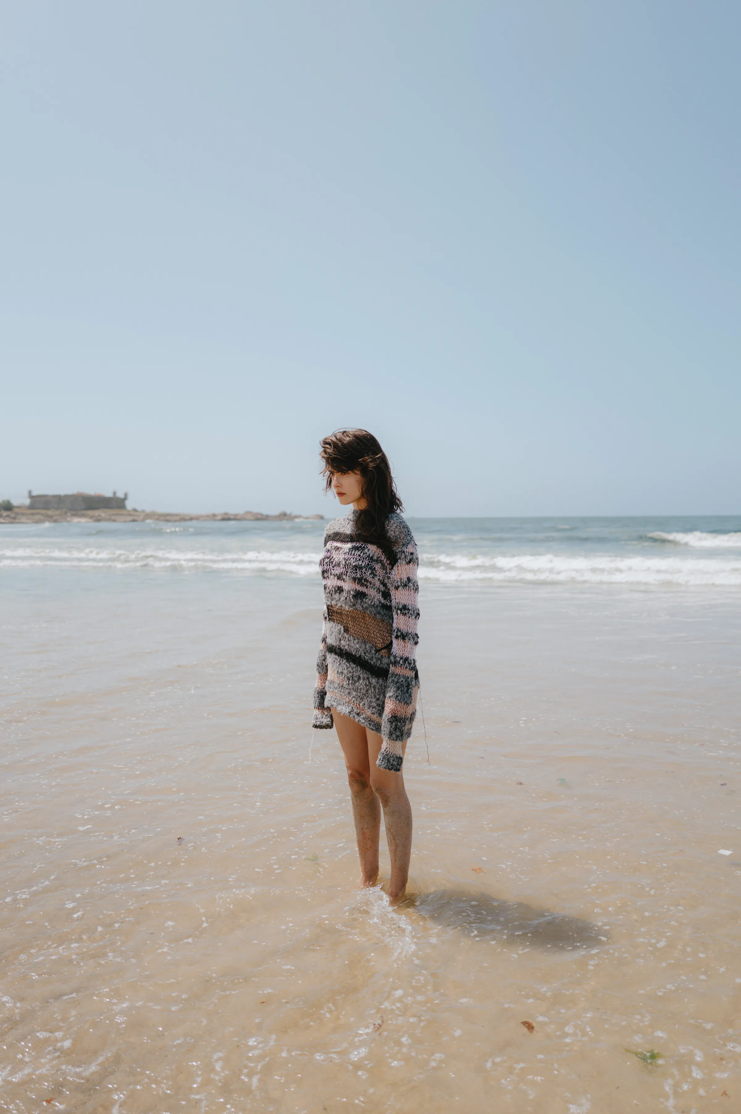 Portrait of a person standing barefoot in shallow water during a seaside outdoor session.