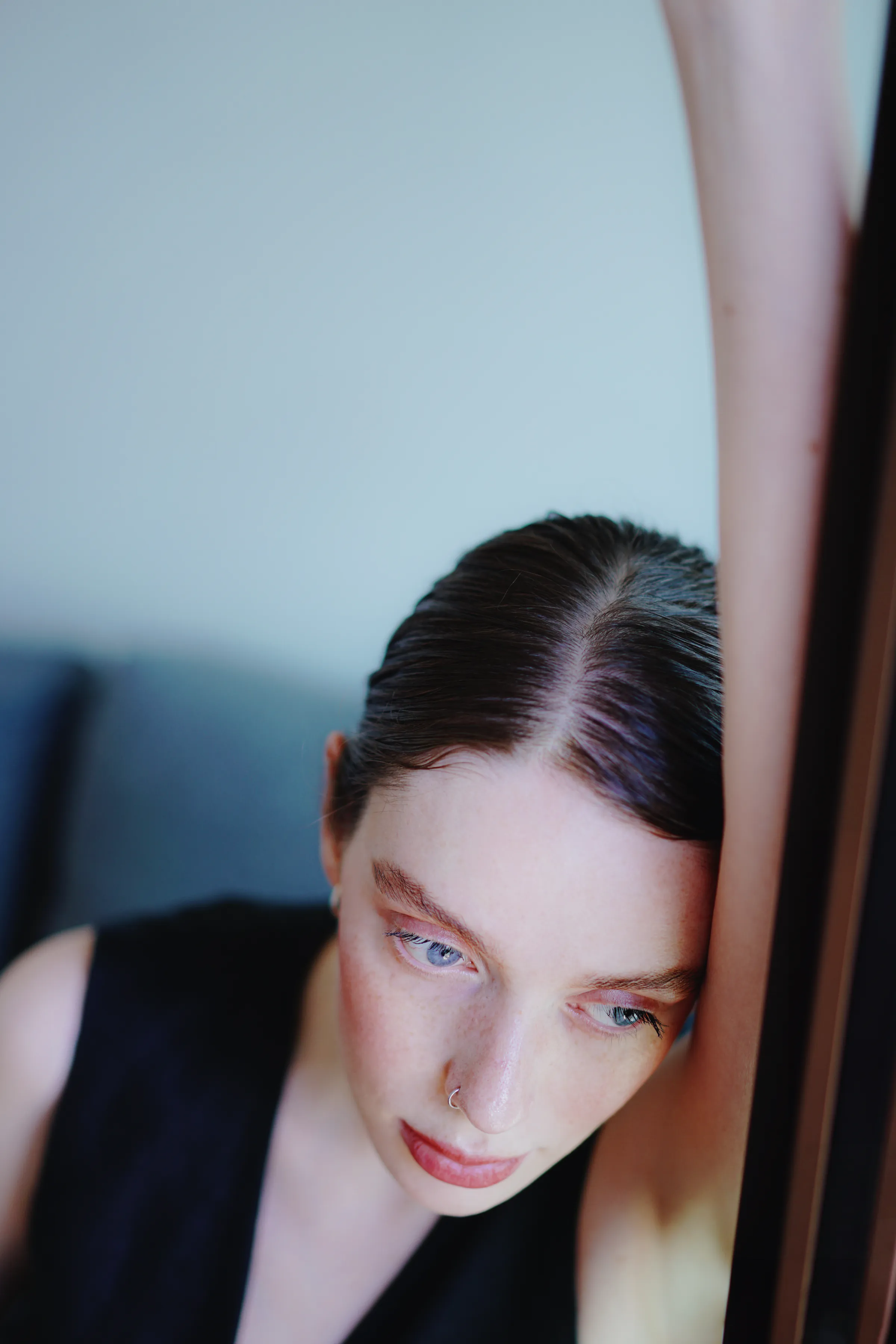Close portrait beside a window or doorway in soft light, with a quiet indoor composition.