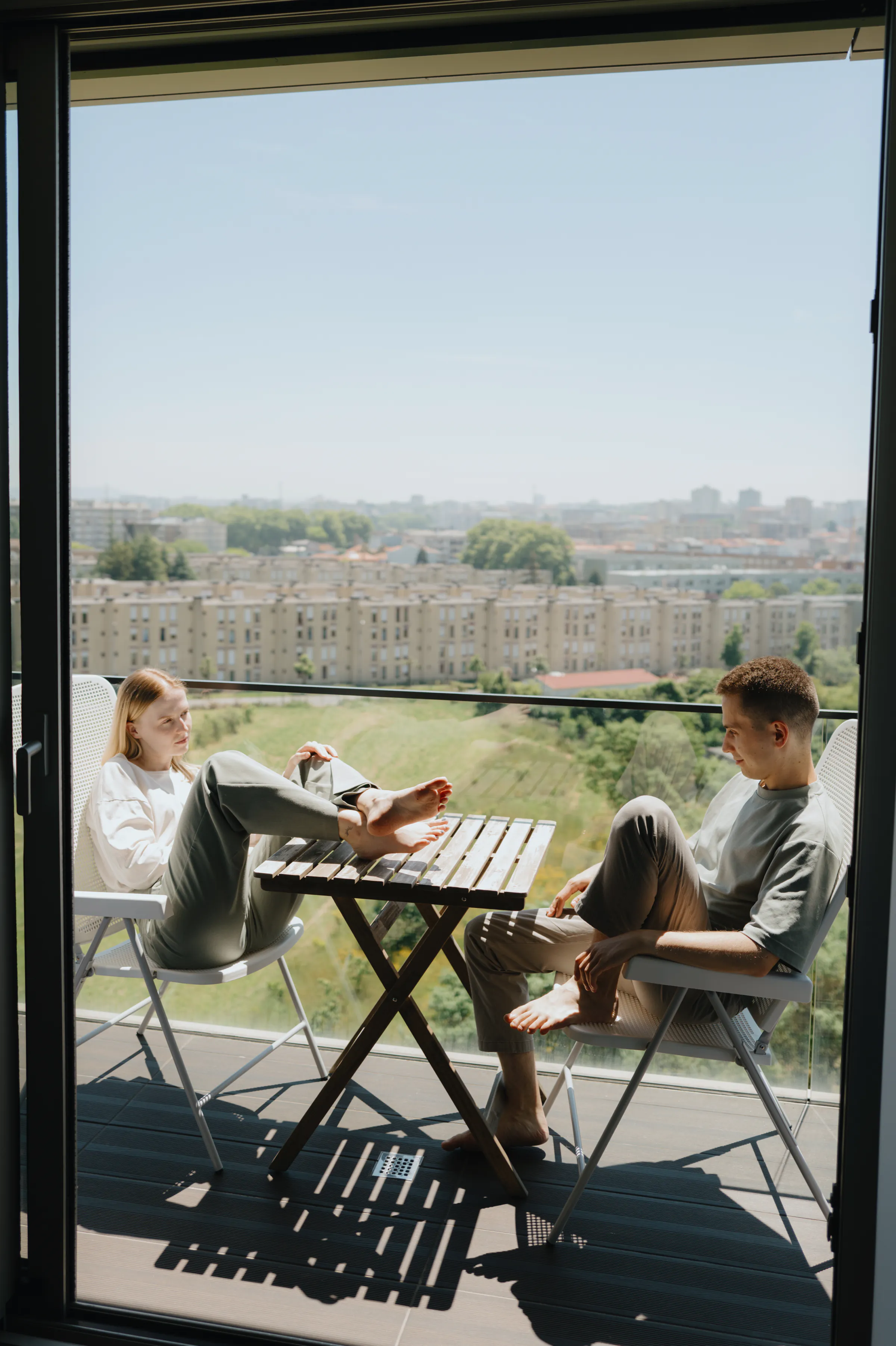 Couple relaxing barefoot on a balcony during a city home session, framed by an open doorway.