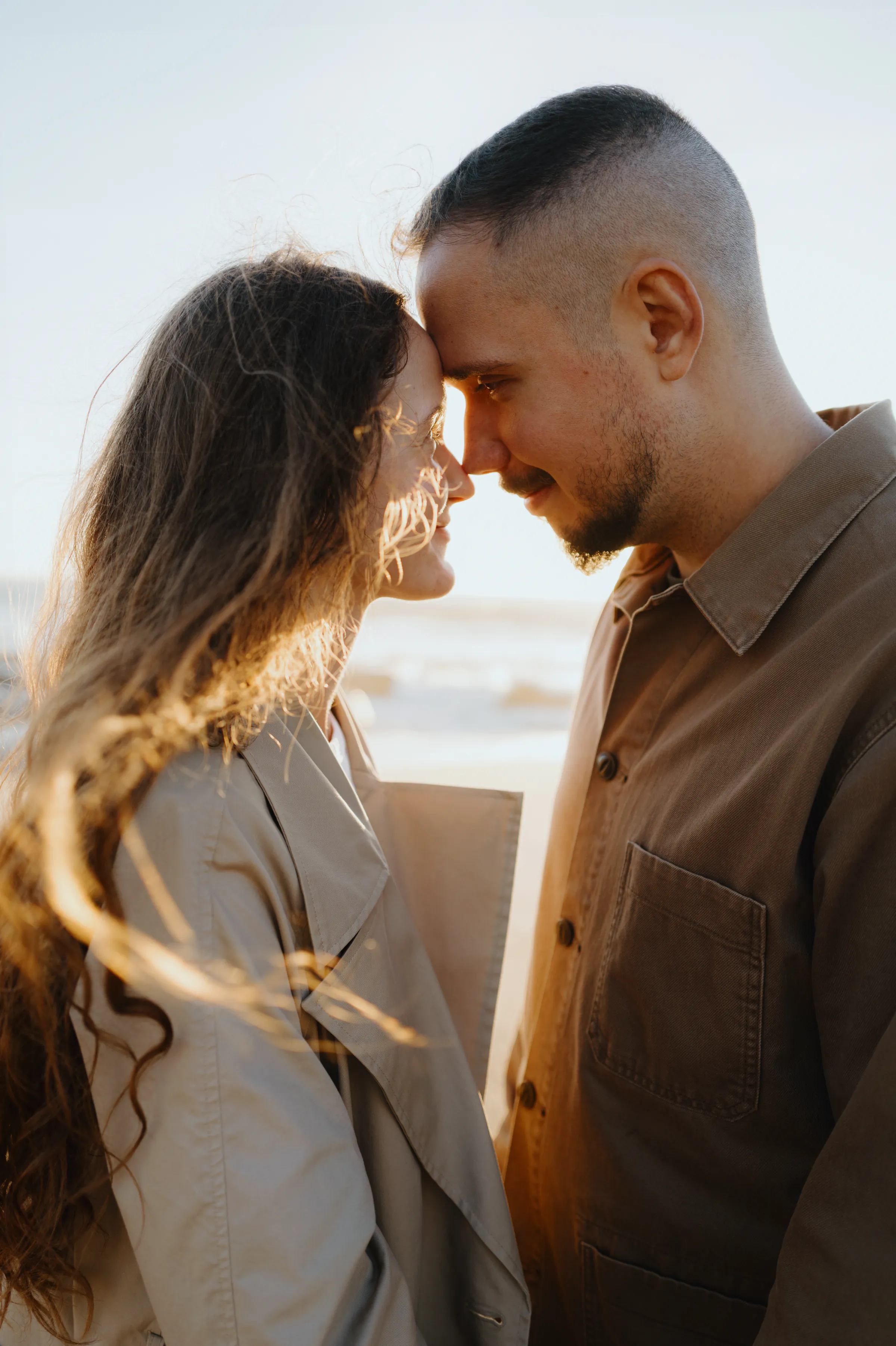 Close portrait of a couple standing face to face during a soft light seaside session.